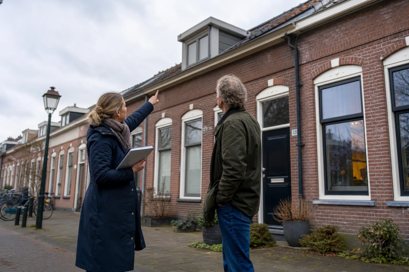 Adviseur bespreekt een mogelijke dakverbouwing met de eigenaar voor zijn woning